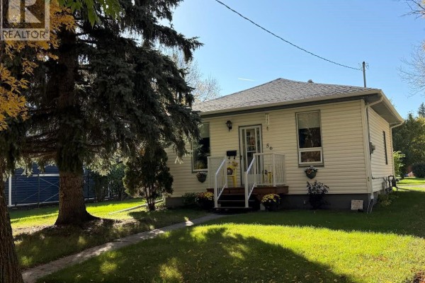 Living room with beige sofa, armchair, recliner, coffee table, and green walls. - 56 Haultain Avenue, Yorkton