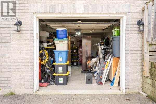 Open garage door revealing storage bins, tools, and gardening equipment inside a two-car garage. - 56 Hersey Crescent, Barrie