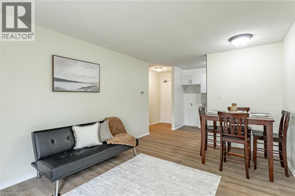 Living and dining area with a black sofa, dining table, and access to the kitchen. - 56 Hiawatha Road Unit# 47, Woodstock