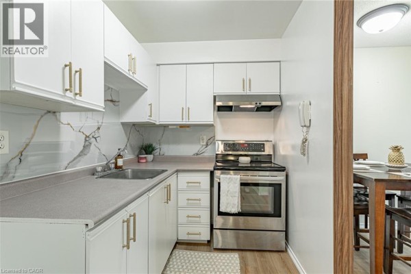 Compact kitchen with white cabinets, stainless steel appliances, and a grey countertop. - 56 Hiawatha Road Unit# 47, Woodstock