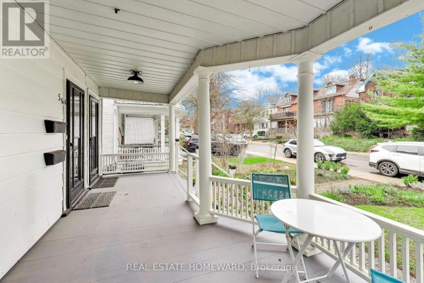 View from the covered front porch looking out to the street, featuring a small white table and chairs. - 56 Leuty Avenue, Toronto