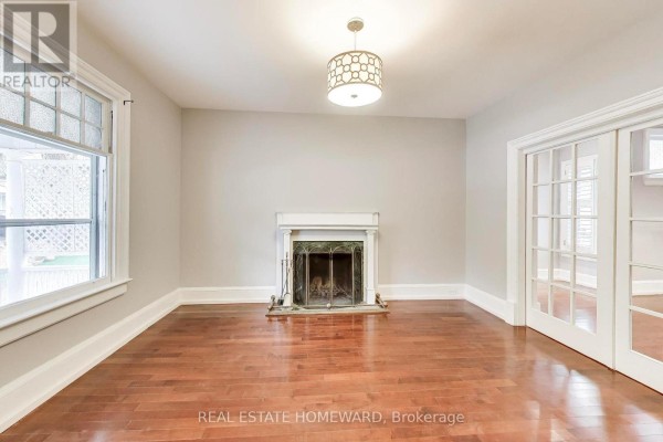 Living room with a fireplace, hardwood floors, and glass-paned double doors leading to another room. - 56 Leuty Avenue, Toronto
