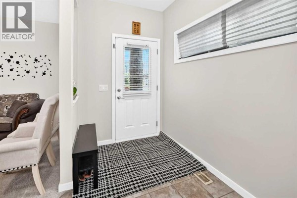 The foyer features a white door with blinds, a black bench, and a patterned rug. - 56 Panatella Parade Nw, Calgary