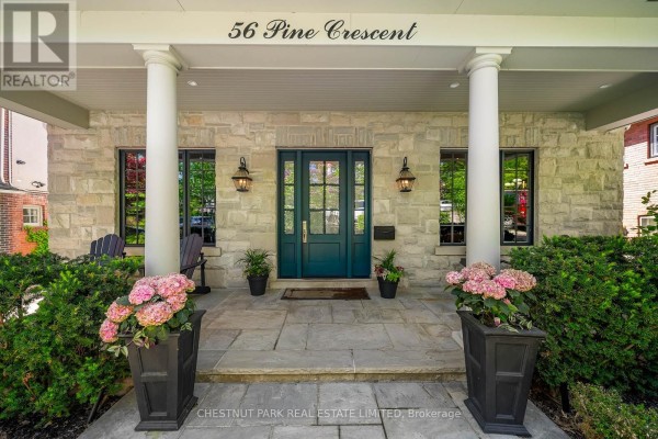 Front entrance of house with stone facade, teal double doors, and porch. - 56 Pine Crescent, Toronto