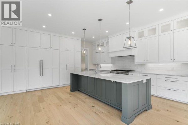 Modern kitchen with white cabinets, gray island, pendant lights, and hardwood floors - 56 Pioneer Ridge Drive Kitchener