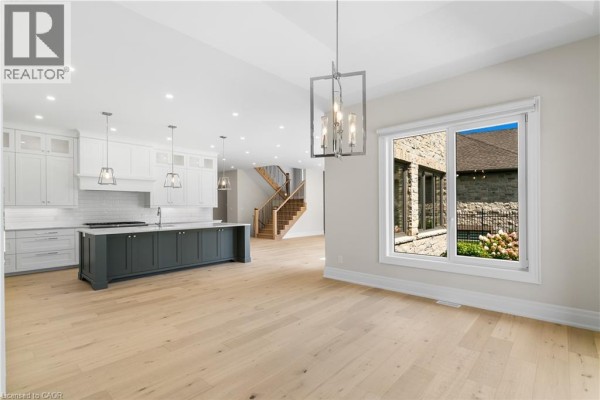 Modern kitchen with island, white cabinets, pendant lights, and hardwood floors - 56 Pioneer Ridge Drive Kitchener