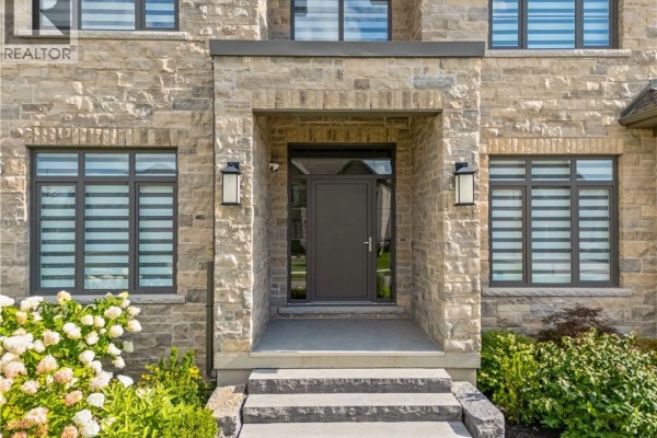 Close-up of the front entrance with a gray door, stone facade, and patterned window blinds. - 56 Pioneer Ridge Drive, Kitchener