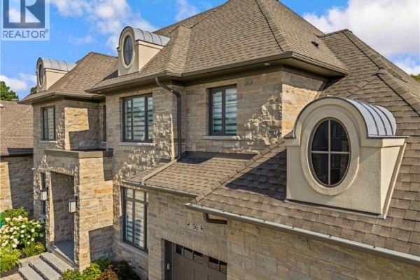 Detail of the upper floors and roofline of a stone house, showing dormer windows. - 56 Pioneer Ridge Drive, Kitchener