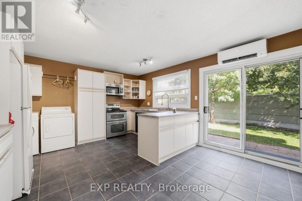 Kitchen with white cabinetry, stainless steel appliances, a center island, and sliding glass doors to the backyard. - 56 Yardley Place, London North