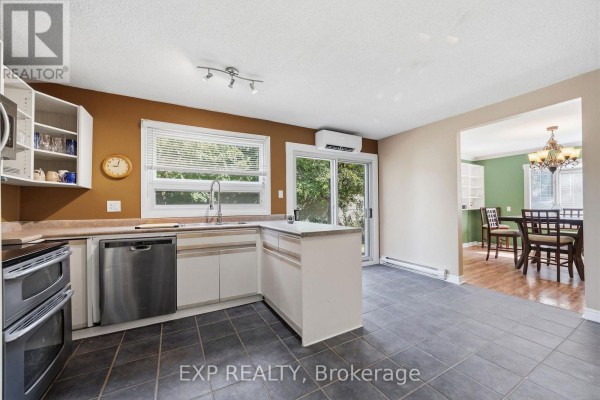 Kitchen with white cabinets, L-shaped counter, stainless steel dishwasher, and a view into the dining room. - 56 Yardley Place, London North