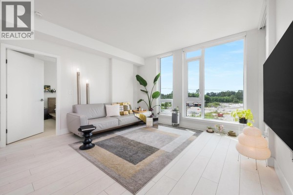 Interior view of a living space with pale wood floors and a large window. - 560 8575 Rivergrass Drive, Vancouver