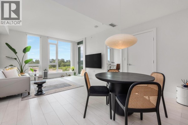 Open concept living and dining area with a round table, chairs, and large windows. - 560 8575 Rivergrass Drive, Vancouver