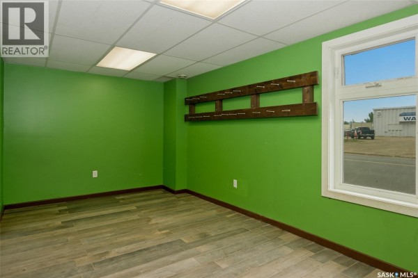 Corner of commercial space with green walls, a large window, and a wooden rack mounted on the wall. - 560 Dewdney Avenue E, Regina