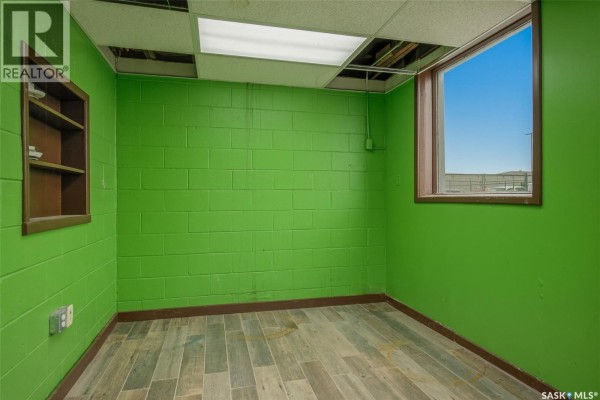 Office space within commercial building with green walls, desk, filing cabinets, and wood-look flooring. - 560 Dewdney Avenue E, Regina