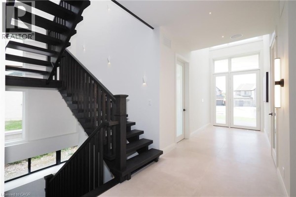 Wide view of a dark wood staircase with white walls and modern sconces. - 560 Werni Court, Waterloo