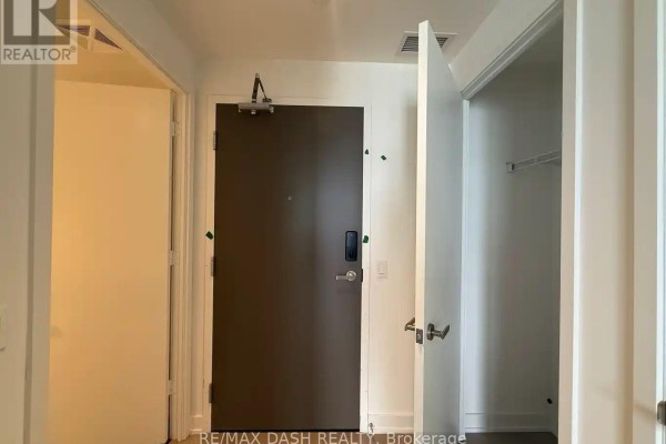 Apartment entrance hallway with a dark brown door, white doors, and an open closet. - 5604 - 448 Burnhamthorpe Road W, Mississauga