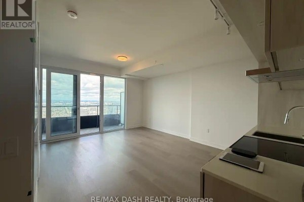 Living room with light wood floors, white walls, and large floor-to-ceiling windows. - 5604 - 448 Burnhamthorpe Road W, Mississauga