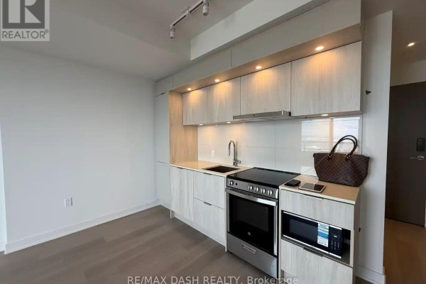 Modern kitchen with light wood cabinets, stainless steel appliances, and a dark countertop. - 5604 - 448 Burnhamthorpe Road W, Mississauga