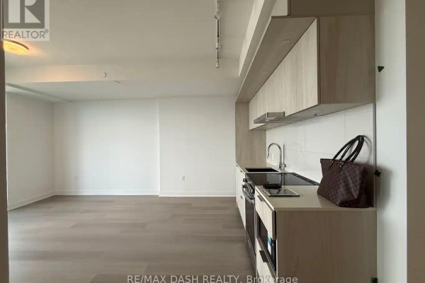 Kitchen area with light wood cabinets, stainless steel stove, and white tiled backsplash. - 5604 - 448 Burnhamthorpe Road W, Mississauga