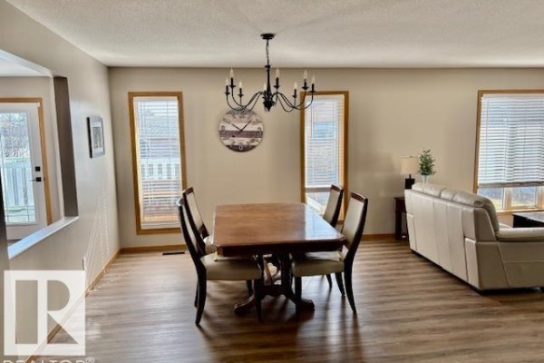 Interior foyer with laminate flooring, dark wood railings, and white interior door. - 5609 45a St, Vegreville