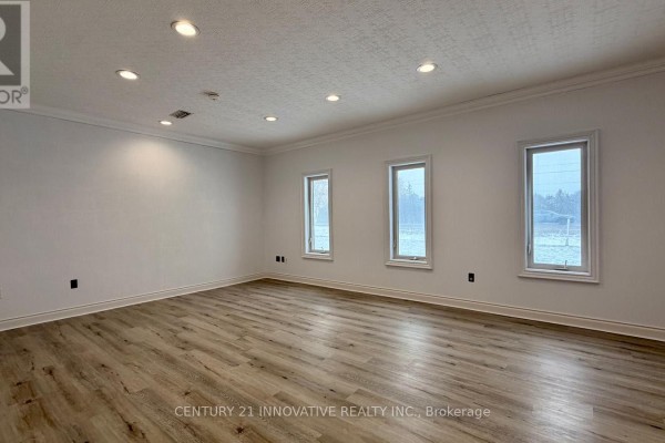 Interior commercial space with light wood laminate flooring, white walls, and three tall windows. - 5615 Mcgillivray Drive N, Lucan Biddulph