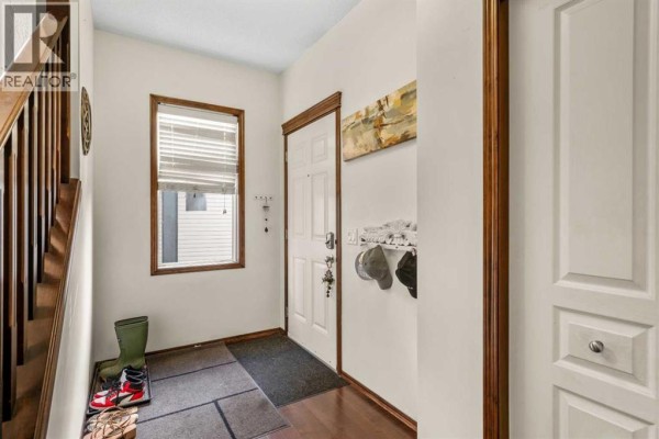 View of the home's entrance with a white door, window, and dark wood flooring. - 562 Cranston Drive Se, Calgary