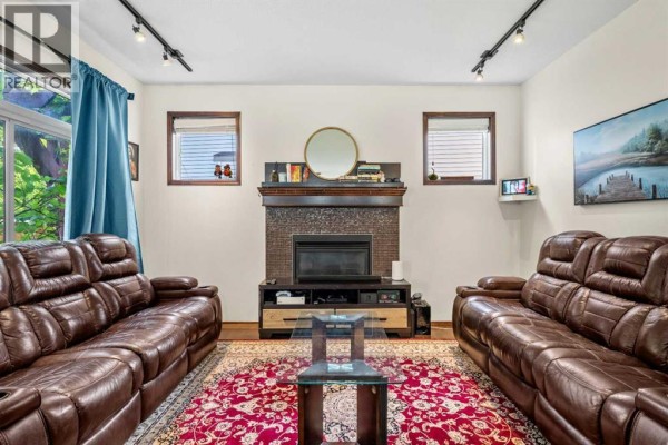 Living room with two brown leather couches, a fireplace, and two windows. - 562 Cranston Drive Se, Calgary