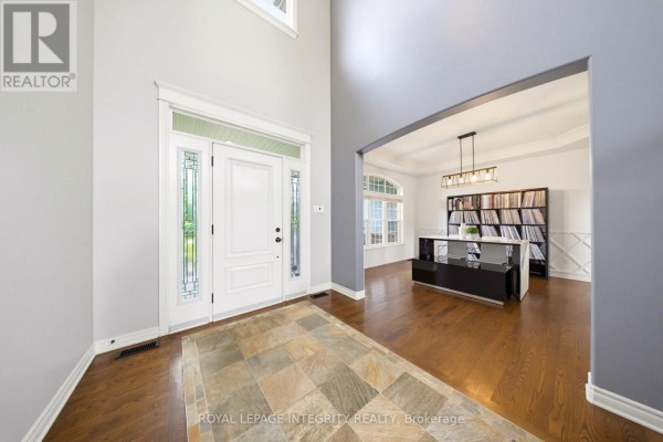 View from inside the foyer looking towards the front door and a sunlit office or den area with large windows. - 562 Pennycross Lane, Ottawa