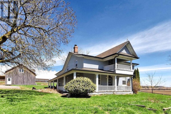Light blue two-story farmhouse with a two-level wrap-around porch and a pitched roof. - 5626 3rd Line, New Tecumseth