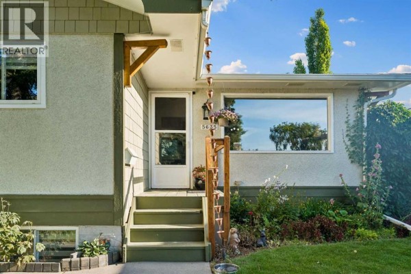 View of the front of the house from the sidewalk, with a concrete path and lawn. - 5635 Travis Crescent Ne, Calgary