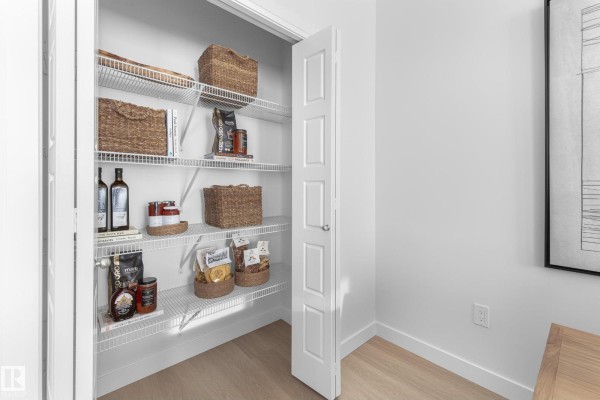 Walk-in pantry with white wire shelving filled with food items and woven baskets. - 5636 Hawthorn Wy Sw, Edmonton