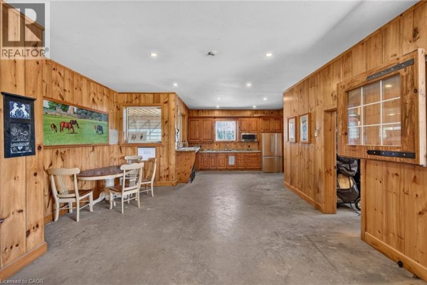 Interior space with wooden paneling, a dining table, and a kitchenette featuring stainless steel appliances. - 564 8th Concession Road E, Carlisle