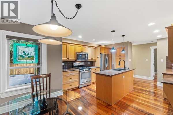 Kitchen with wood cabinets, stainless steel appliances, and a central island with pendant lights. - 564 Hazelwood Pl, Qualicum Beach