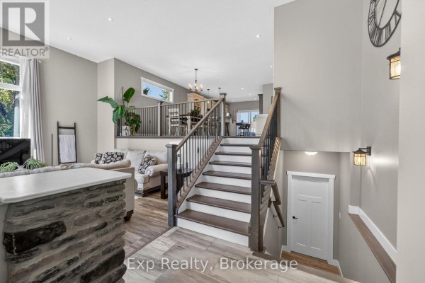 View from the entrance showing a staircase with dark railings and open-concept living areas. - 564 Sidney Street, Belleville