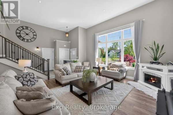 Spacious living room with a large window, fireplace, sectional sofa, and a large wall clock. - 564 Sidney Street, Belleville