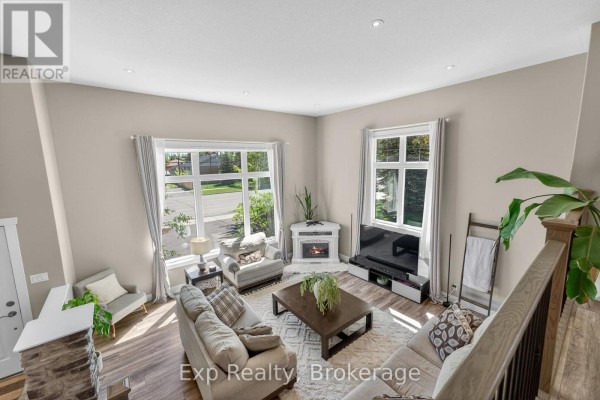 High-angle view of a living room with two sofas, a coffee table, fireplace, and large windows. - 564 Sidney Street, Belleville