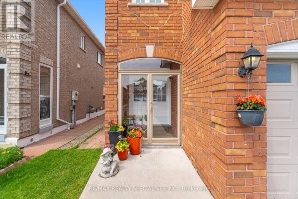 Close-up of the arched glass entryway of a brick house with potted plants. - 5642 Armando Avenue, Mississauga