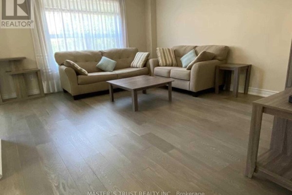 Living room with two beige sofas, a coffee table, and light wood flooring. - 5659 Dolmite Heights, Mississauga