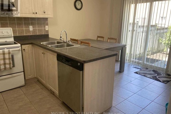 Kitchen with white appliances, granite countertops, light wood cabinets, and a sliding door. - 5659 Dolmite Heights, Mississauga