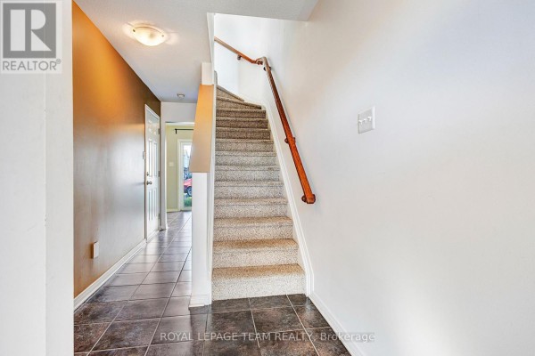 Interior hallway with tiled floor, a carpeted staircase, and a closet. - 566 Simran Private, Ottawa