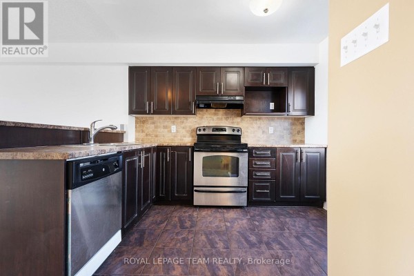 U-shaped kitchen with dark brown cabinets, stainless steel appliances, and tiled floor. - 566 Simran Private, Ottawa
