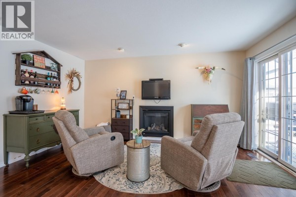 Living room featuring a gray sectional sofa, hardwood flooring, and a dining area with a table - 5663 Horse Lake Road, 100 Mile House