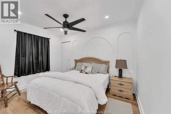 Bedroom with king bed, ceiling fan, nightstand, chair, black curtains - 567 Edinborough Windsor
