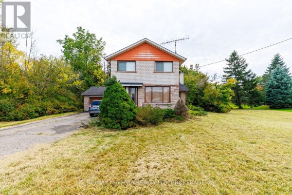 Front view of a two-story house with orange trim, brick and stone facade, and an attached garage. - 567 Lyons Creek Road, Welland