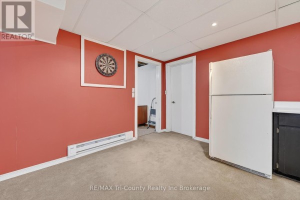 Basement with dartboard, refrigerator, and red walls - 568 7th Concession Enr Road Norfolk