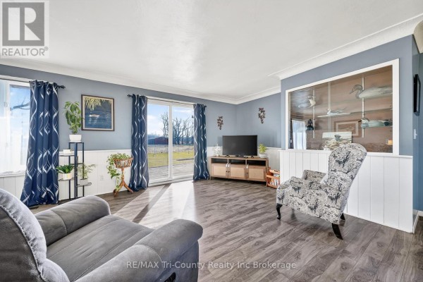 Living room with blue walls, decoys in display cabinet, and view to backyard - 568 7th Concession Enr Road Norfolk