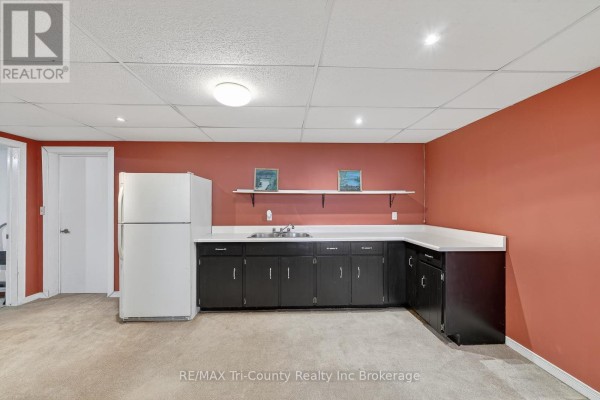 Basement kitchen with refrigerator, dark cabinets, and sink - 568 7th Concession Enr Road Norfolk
