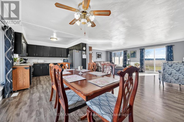 Wooden dining table and chairs in open-concept dining room with kitchen and field view - 568 7th Concession Enr Road Norfolk