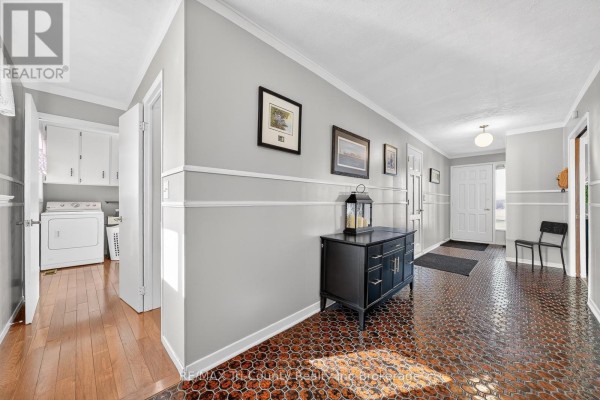 Hallway with geometric tile floor, console table, artwork, and laundry area - 568 7th Concession Enr Road Norfolk