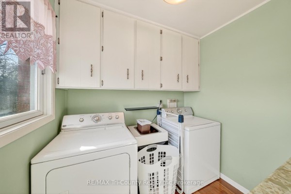Laundry room with white cabinets, washer, dryer, and laundry basket - 568 7th Concession Enr Road Norfolk